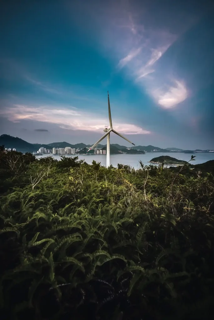 Wind turbine standing in a green field with the sea in the background